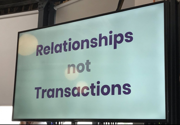 Photo of large screen with blue text on that reads Relationships not transactions