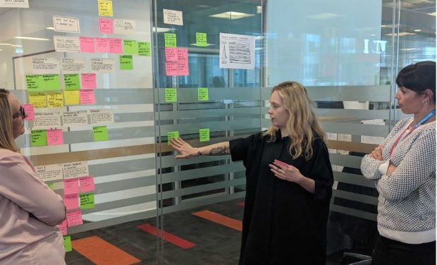 three female members of the team plotting out post-it notes on a glass wall