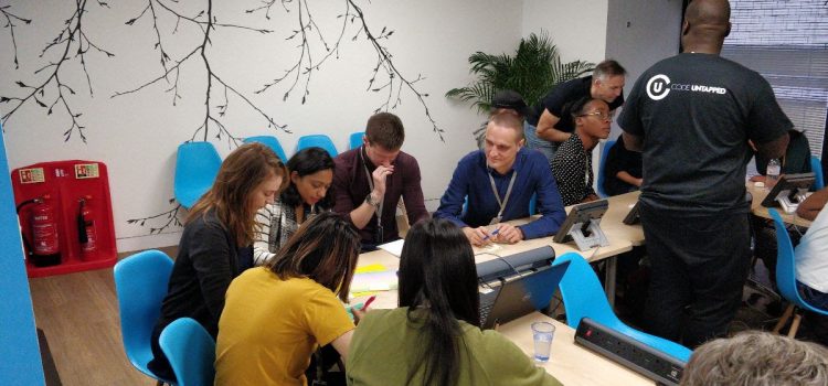 About 10 people sitting in a group concentrating and conferring.