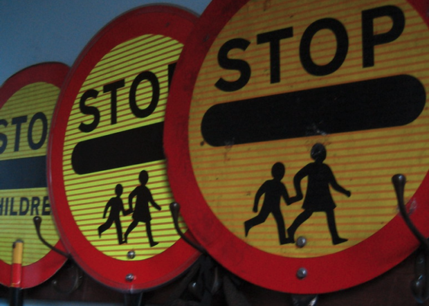 3 signs positioned side by side that warn road users to 'stop - children crossing'. Otherwise known as lollipop signs