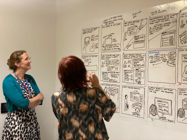 DfE’s Permanent Secretary discussing our storyboard with one of our team members. The story board shows the journey of a user encountering a problem and then using our service to remedy it.