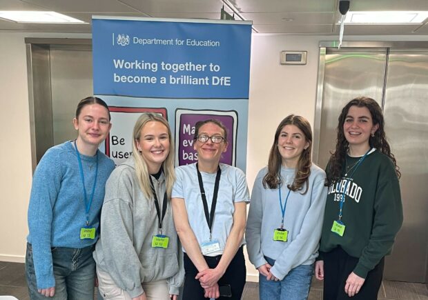 5 women smiling stood in front of a banner reading 'working together to become a brilliant DfE'